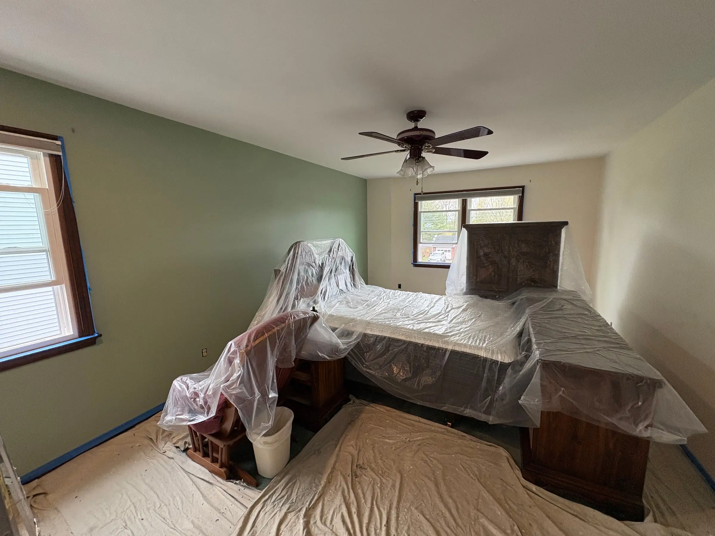 Bedroom prepared for painting with furniture covered in protective plastic