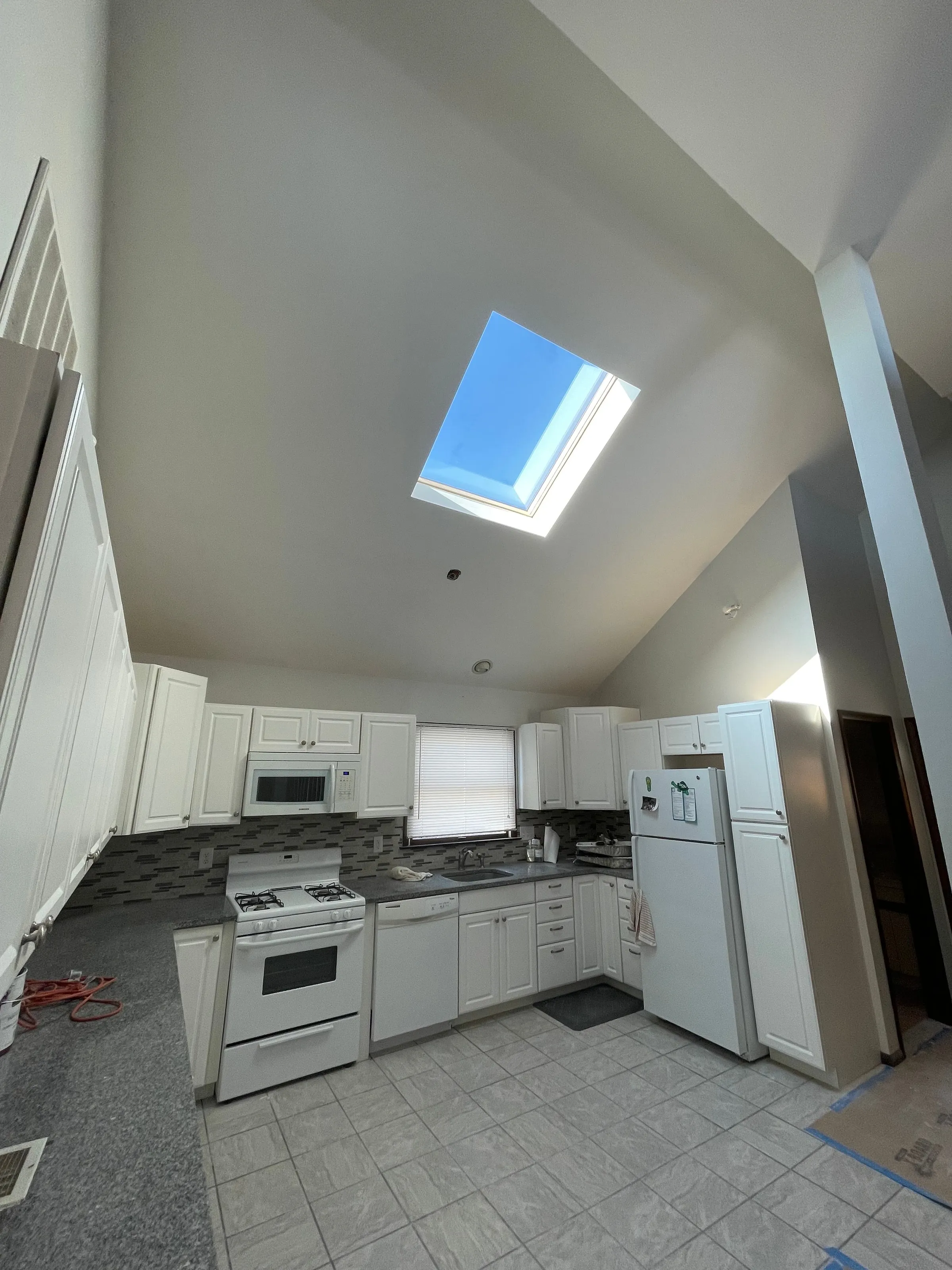Kitchen with vaulted ceiling and skylight painted in white