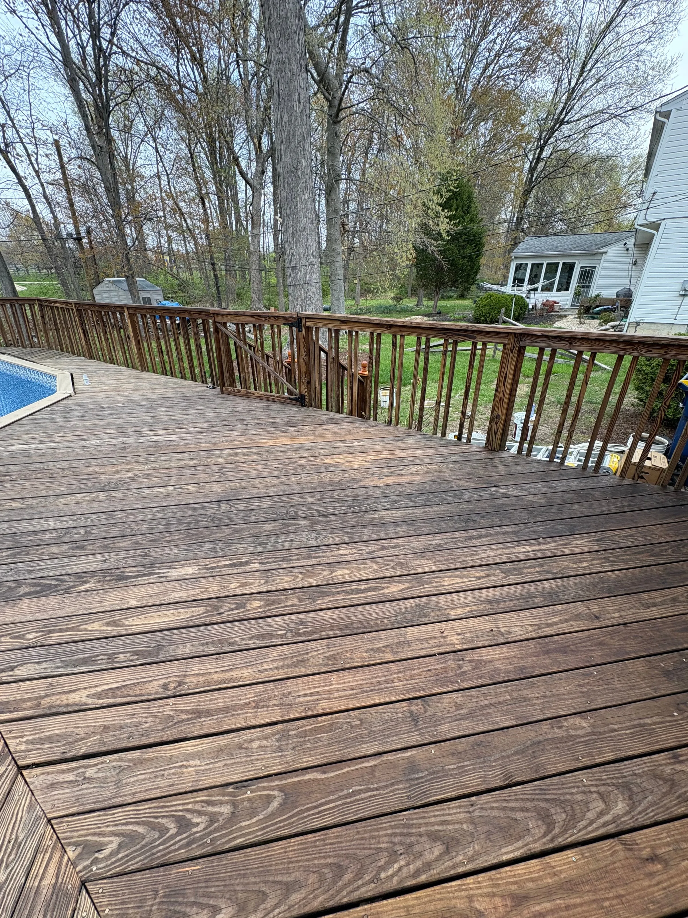 Large wooden deck overlooking a back garden, prepared for staining