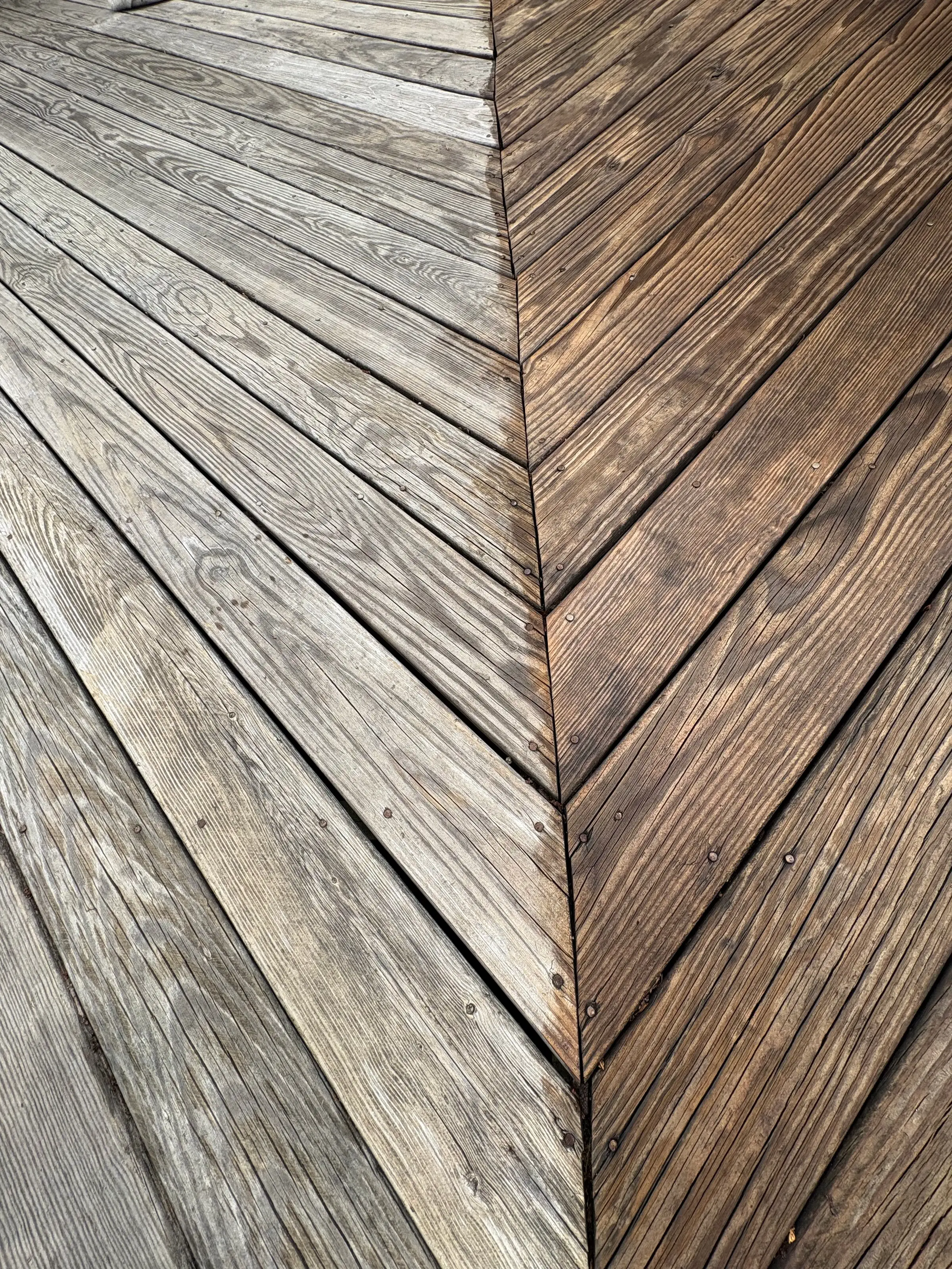 Weathered deck boards in a herringbone pattern before staining