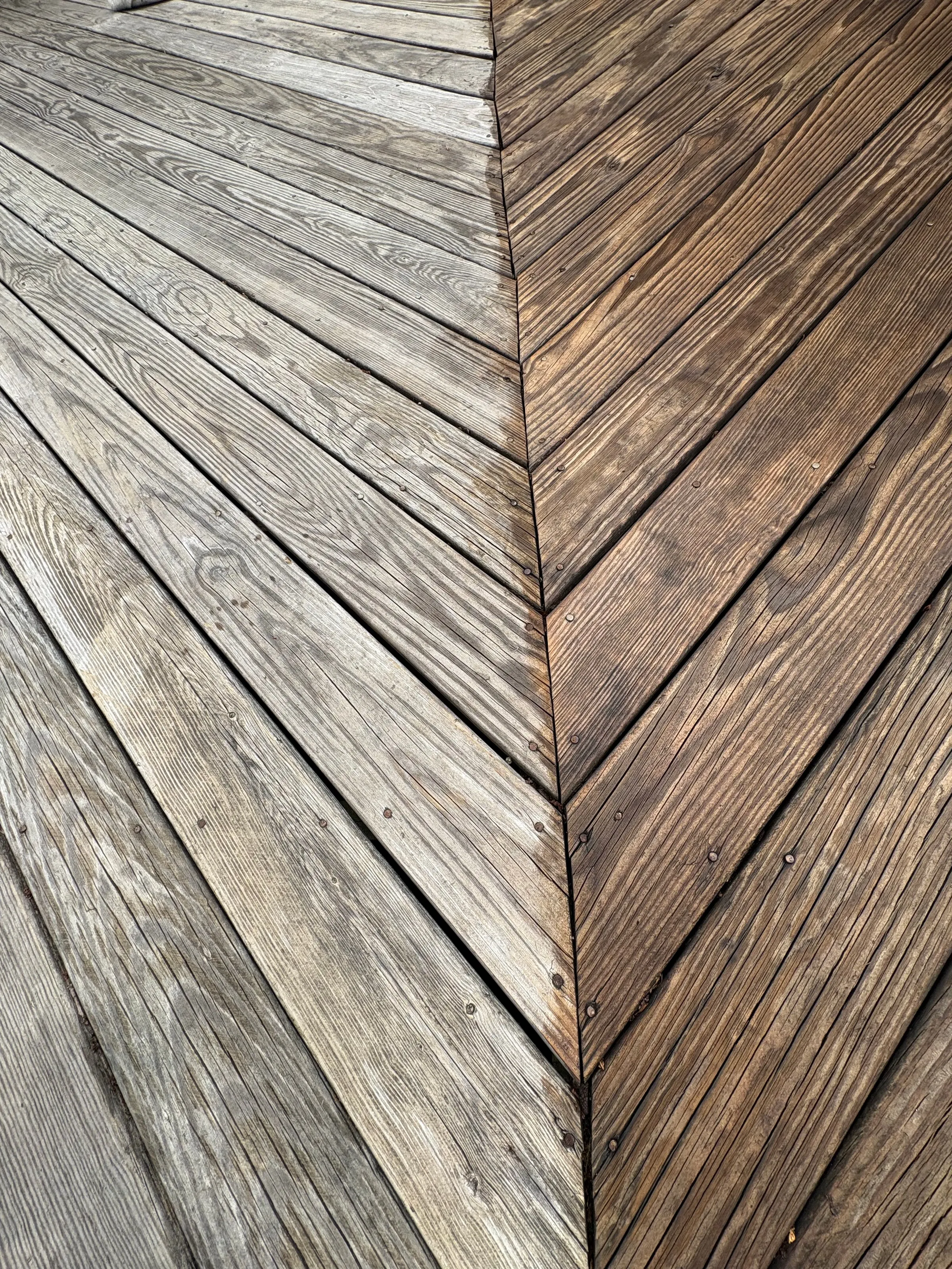 Weathered deck boards in a herringbone pattern before staining
